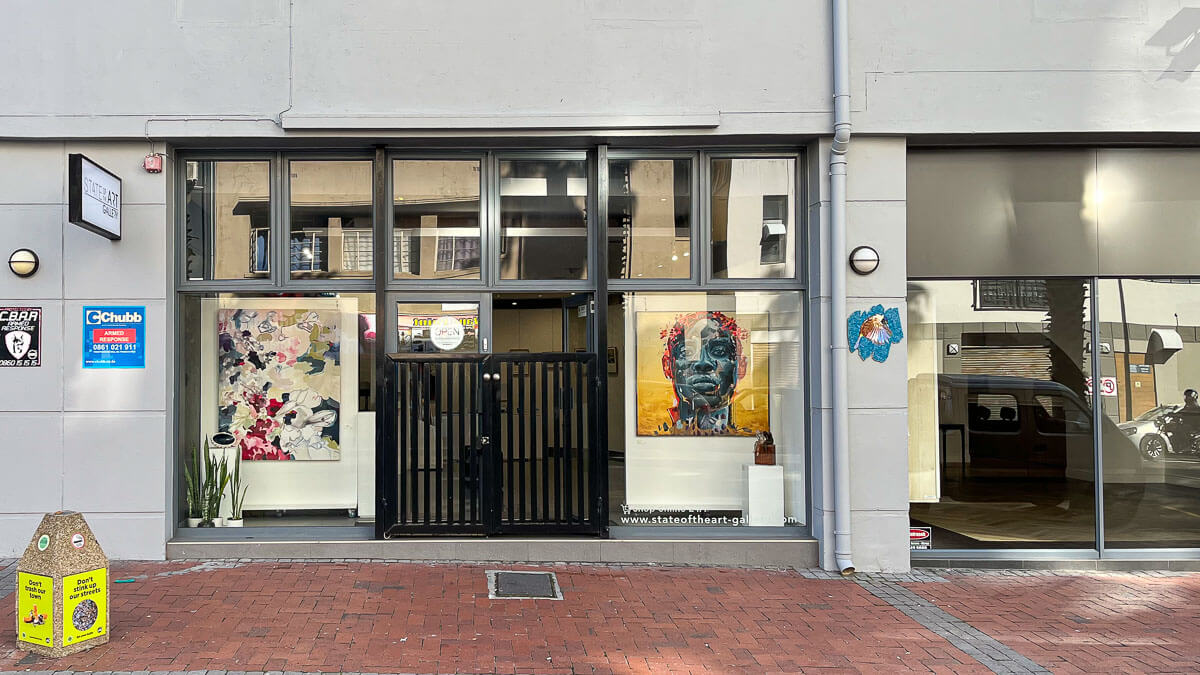 StateoftheART Gallery on Buitenkant Street. The mosaic bomb to the left of the Gallery entrance and contemporary art is visible through the windows.